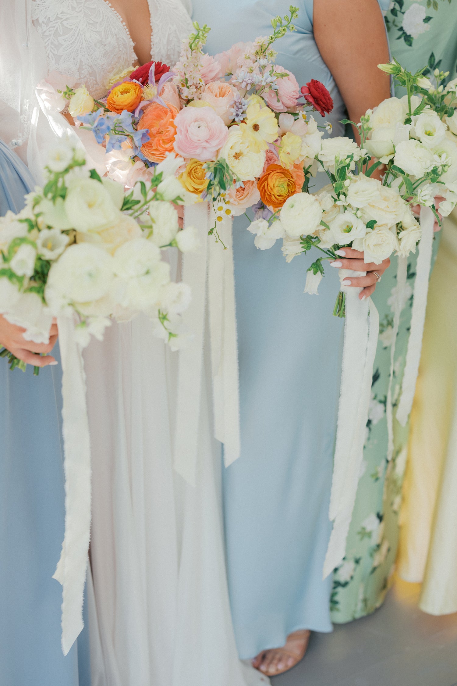 Bridesmaids holding colorful floral bouquets with ribbons. Lush garden wedding florals Atlanta