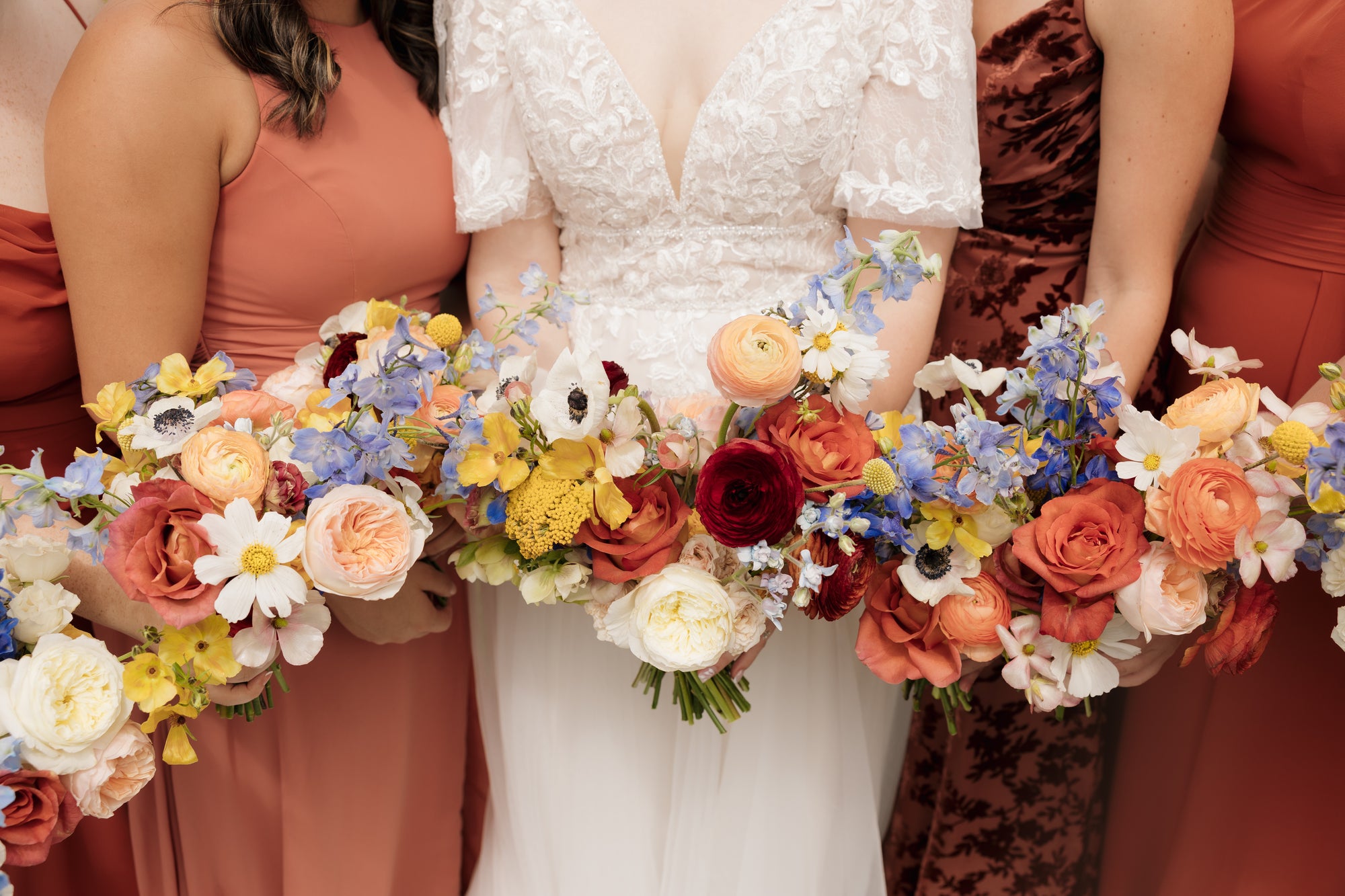 Bride holding a bouquet with bridesmaids in colorful dresses.
