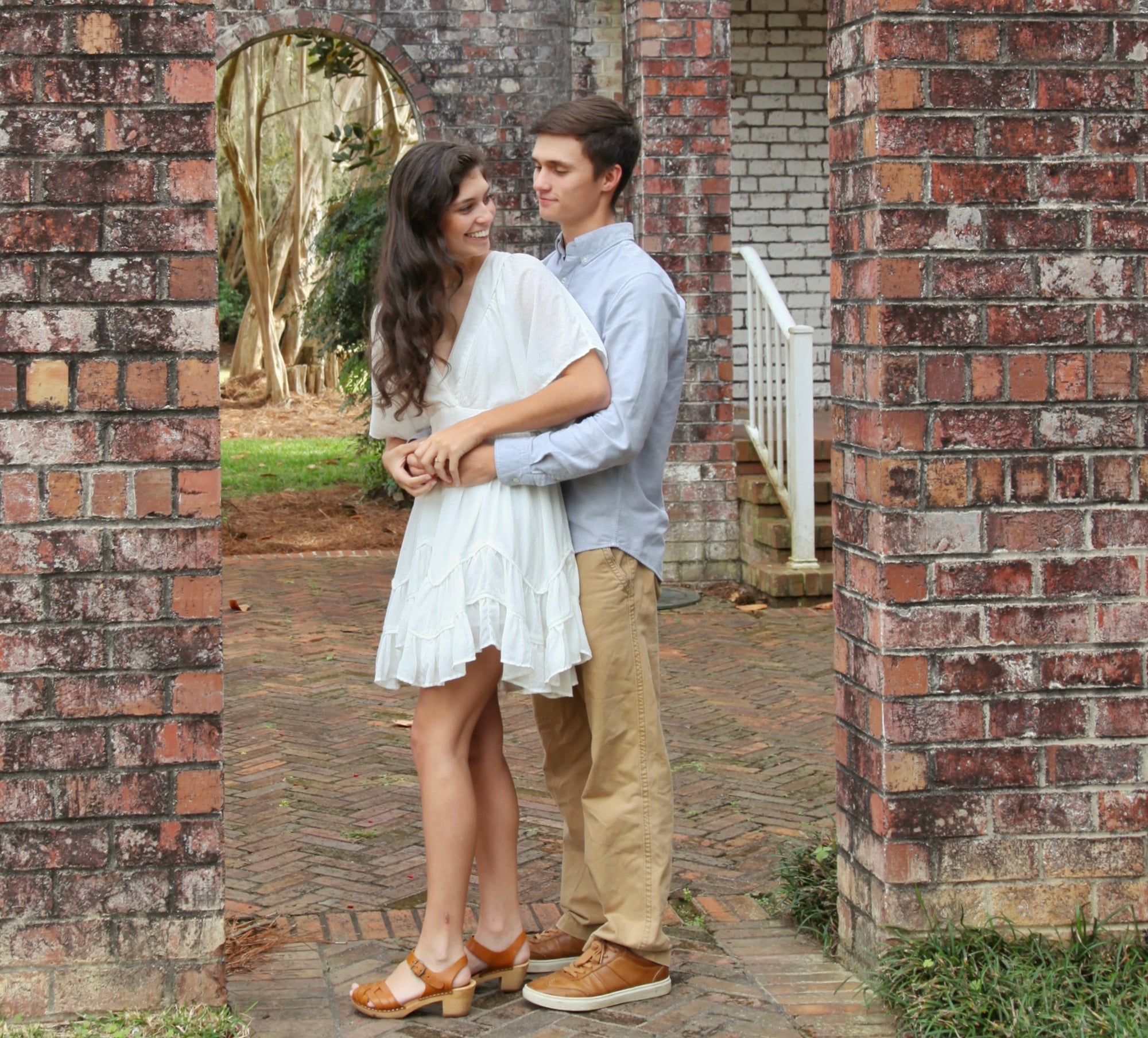 Couple embracing in front of a brick archway