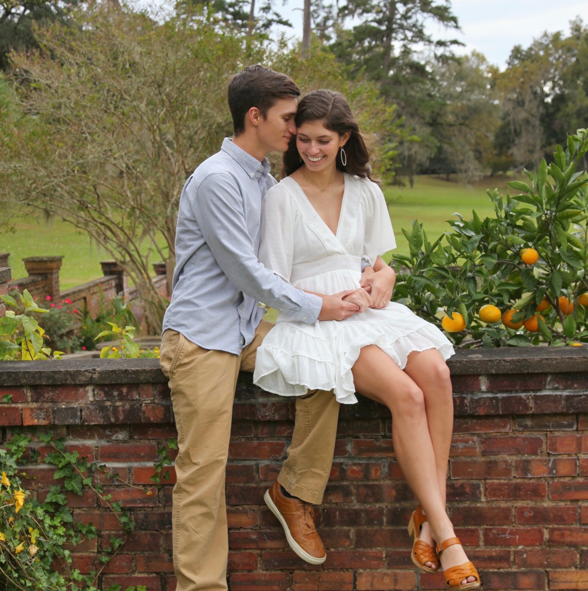Couple sitting on a brick wall in a garden setting