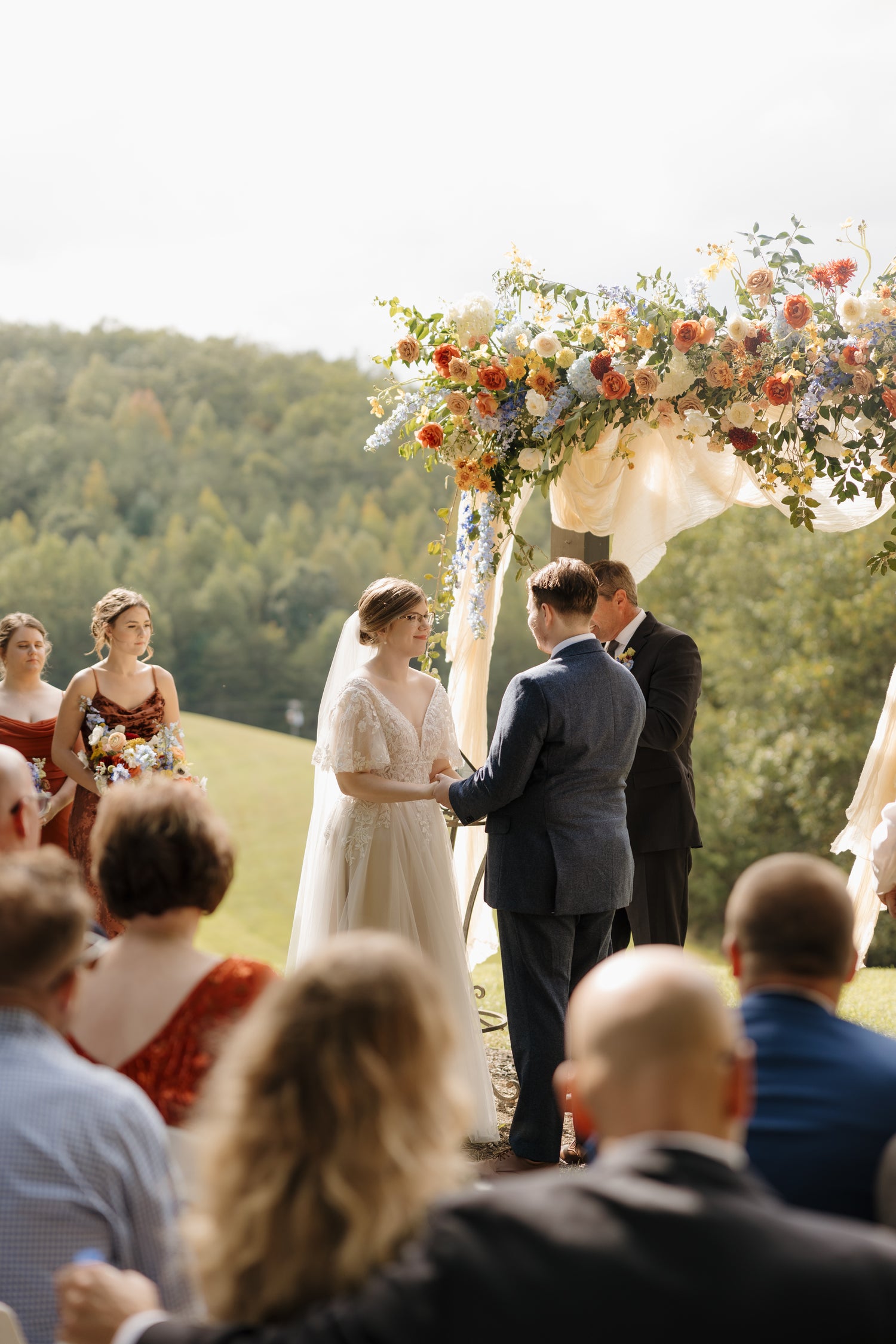 Wedding ceremony with a floral arch and guests in an outdoor setting. Lush garden wedding floral arch in Atlanta