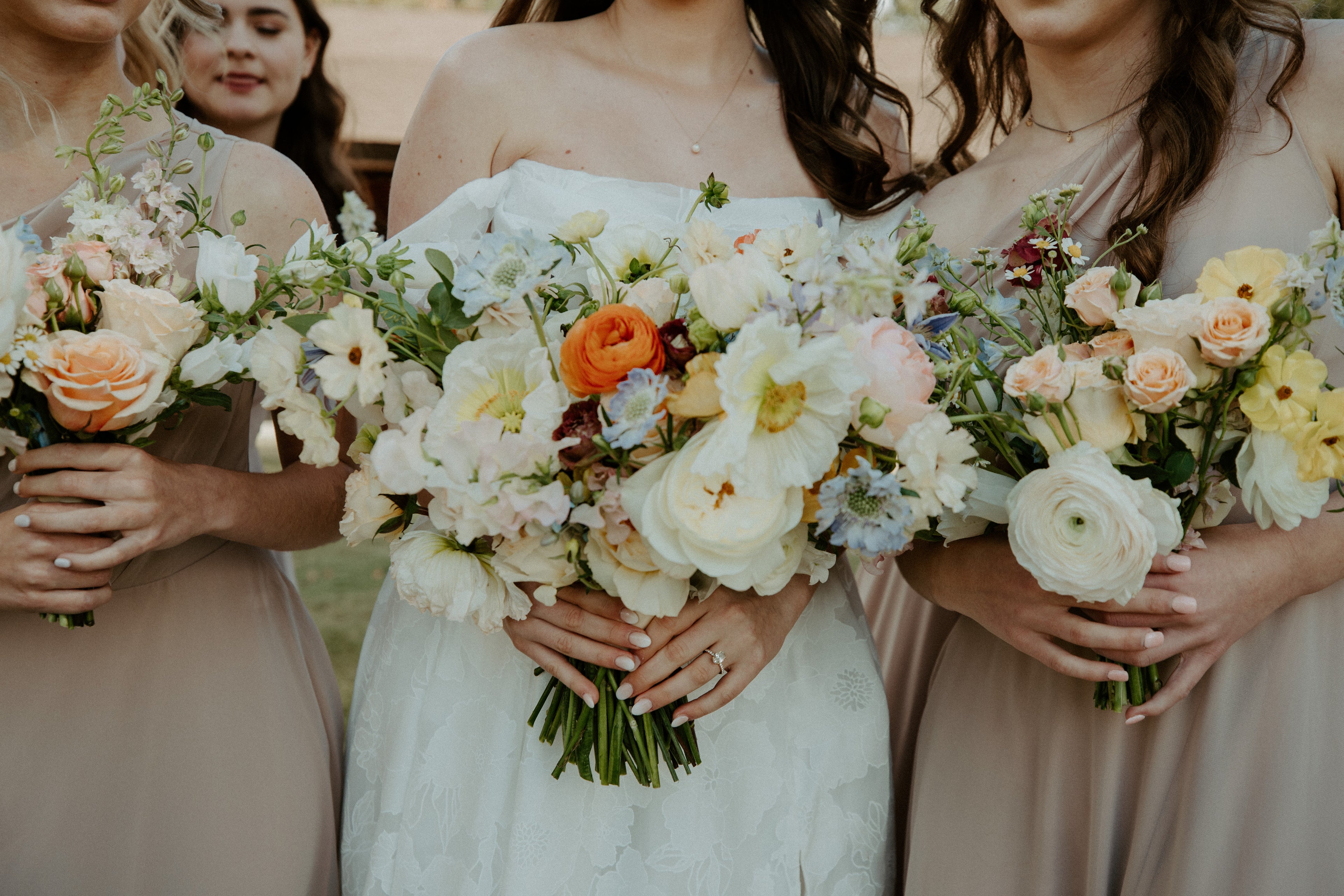 bride and bridesmaids holding soft pastel color bouquets, white bouquets