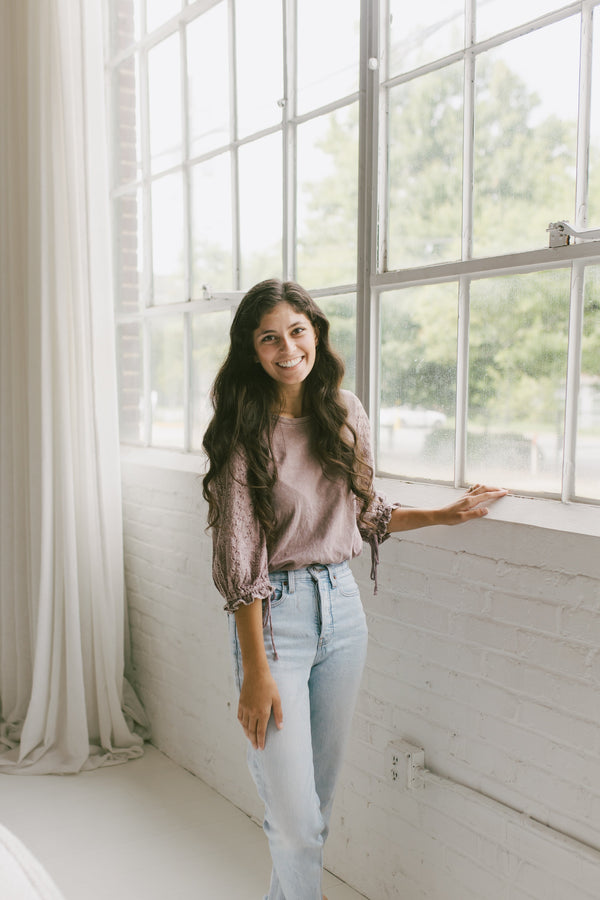 Amber Payton, owner of refined studio standing in a bright room with large windows and white walls.