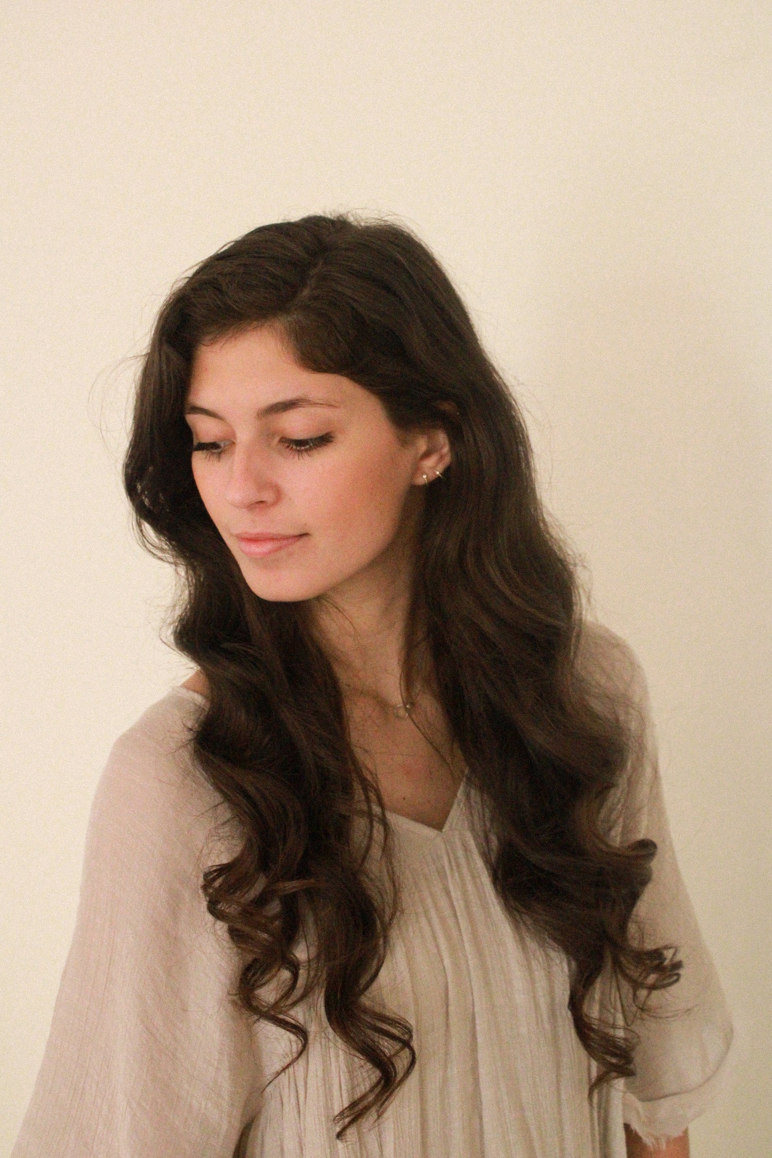 Woman with long, wavy hair wearing a light-colored top against a plain background, atlanta florist, amber payton, wedding florist in atlanta