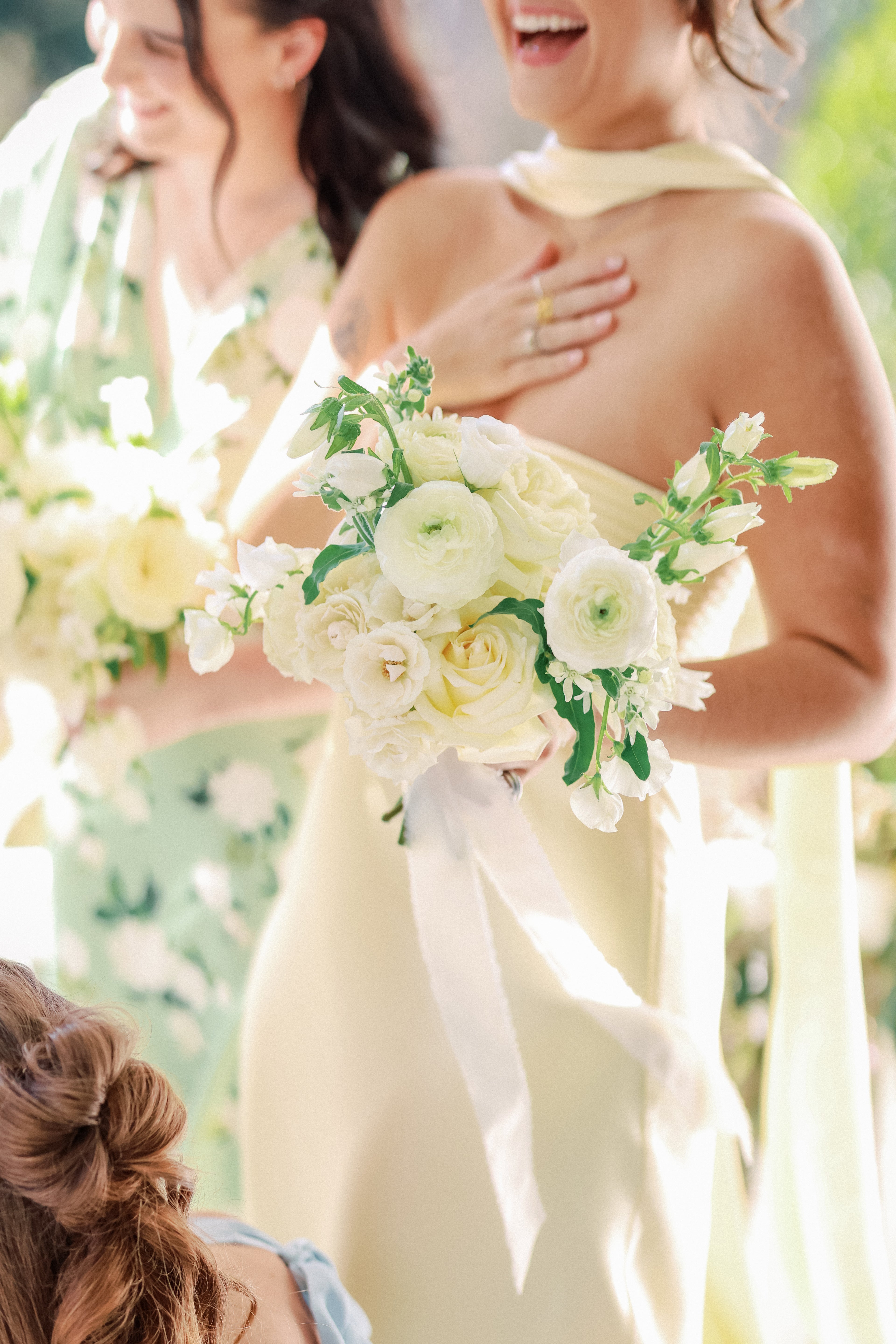 girl holding white bridesmaid bouquet with flowing ribbon, garden style flowers