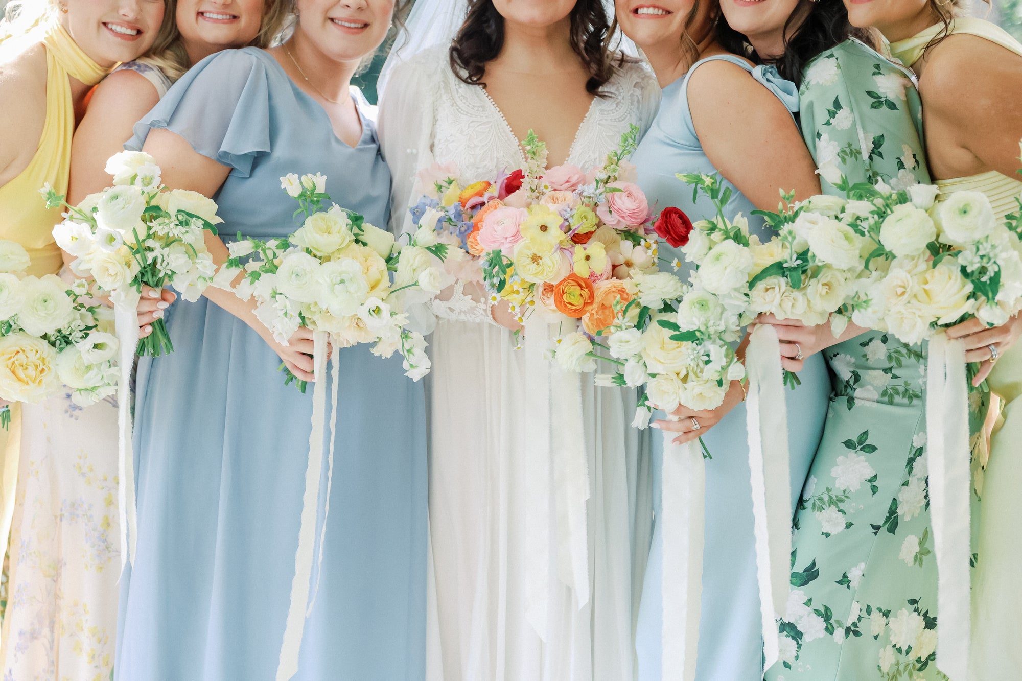 Bride with bridesmaids holding colorful bouquets in a celebratory setting